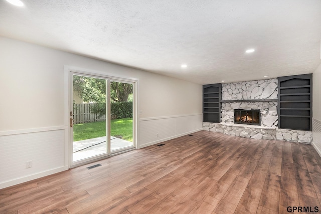801 Redwood Ln, Papillion, NE 68046 - unfurnished living room with wainscoting, a stone fireplace, wood finished floors, built in shelves, and recessed lighting