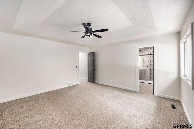 801 Redwood Ln, Papillion, NE 68046 - unfurnished bedroom featuring light colored carpet, a tray ceiling, a textured ceiling, connected bathroom, and a ceiling fan
