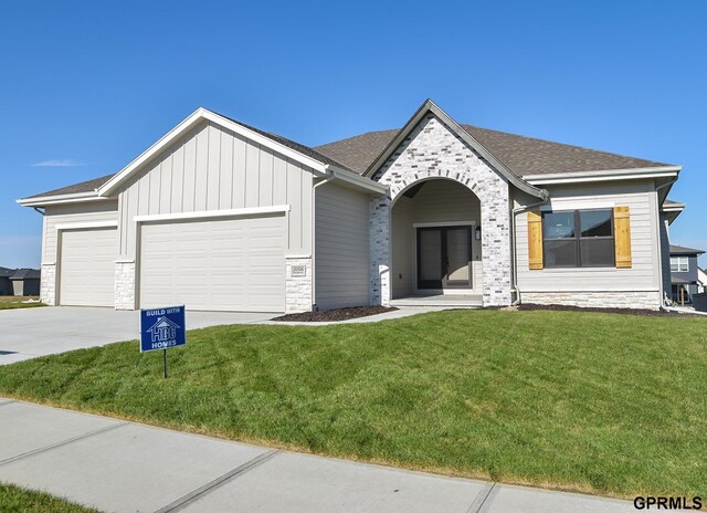 20506 Boulder St, Gretna, NE 68028 - view of front of property featuring a garage, concrete driveway, a front lawn, stone siding, and roof with shingles