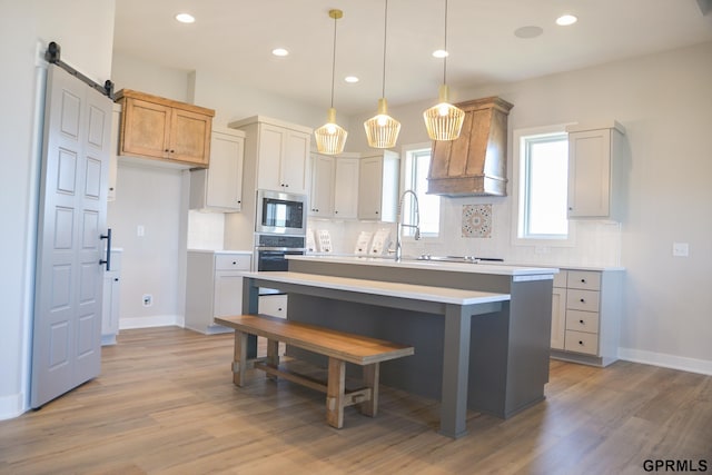 20506 Boulder St, Gretna, NE 68028 - kitchen with backsplash, stainless steel appliances, light countertops, custom exhaust hood, and light wood finished floors