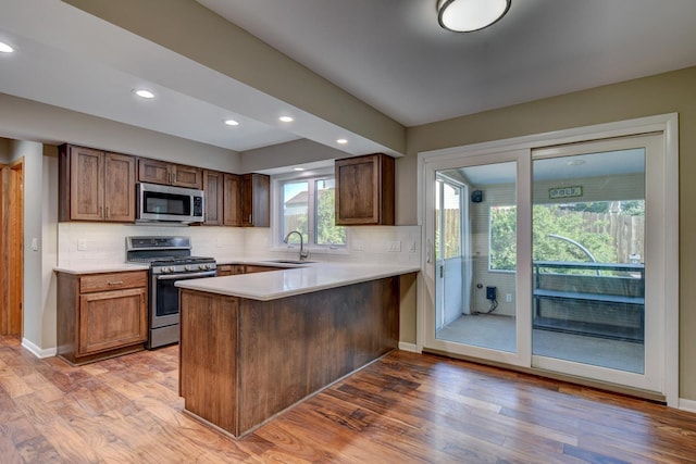 16712 Gold St, Omaha, NE 68130 - kitchen featuring appliances with stainless steel finishes, a peninsula, tasteful backsplash, light wood-type flooring, and light countertops