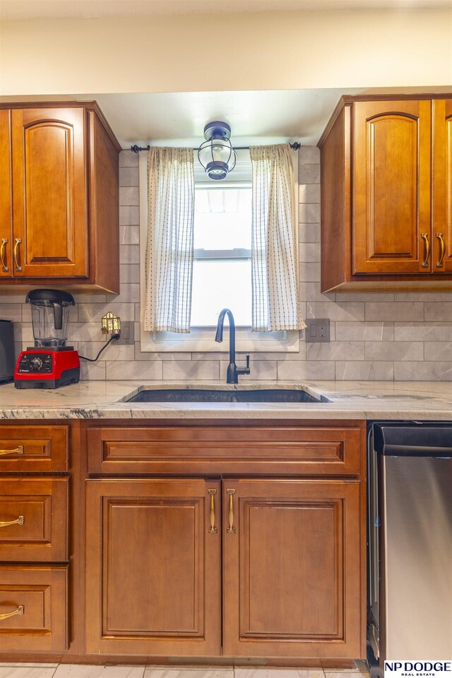 1211 Devon Dr, Papillion, NE 68046 - kitchen featuring stainless steel dishwasher, brown cabinets, backsplash, and light stone countertops