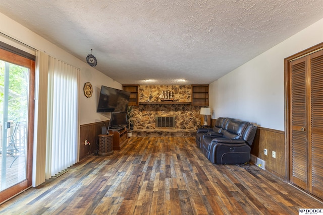 1211 Devon Dr, Papillion, NE 68046 - living area featuring dark wood finished floors, a textured ceiling, a stone fireplace, a wainscoted wall, and wooden walls