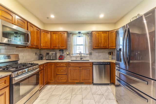 1211 Devon Dr, Papillion, NE 68046 - kitchen featuring stainless steel appliances, brown cabinetry, light marble finish flooring, backsplash, and light stone countertops