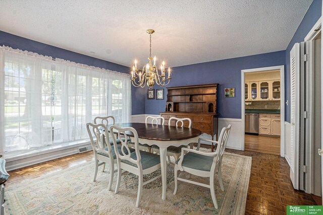 1729 S 76th Ave, Omaha, NE 68124 - dining room with a chandelier, a textured ceiling, and wainscoting