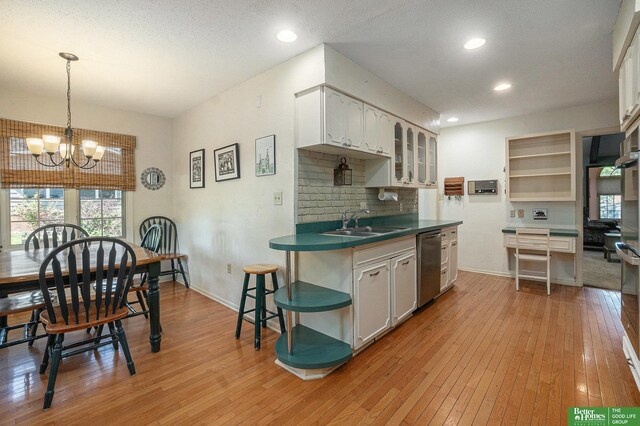 1729 S 76th Ave, Omaha, NE 68124 - kitchen with dishwasher, light wood-style floors, a chandelier, dark countertops, and glass insert cabinets