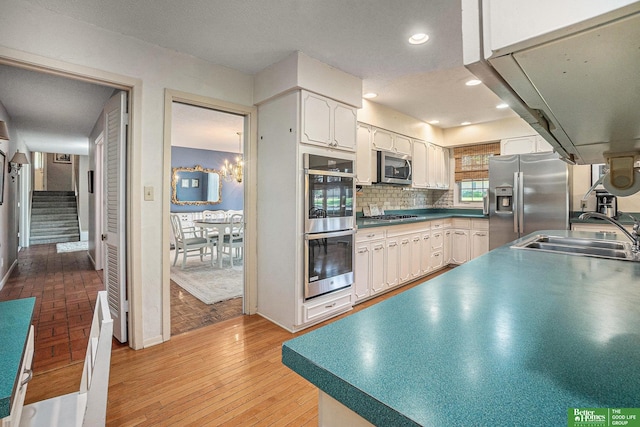 1729 S 76th Ave, Omaha, NE 68124 - kitchen with stainless steel appliances, white cabinetry, decorative backsplash, recessed lighting, and light wood-style flooring