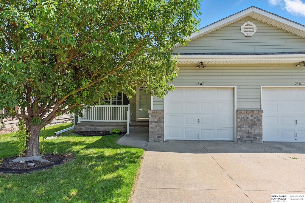 1507 23rd Ave, Council Bluffs, IA 51501 - view of front of property featuring concrete driveway, a front lawn, covered porch, and brick siding
