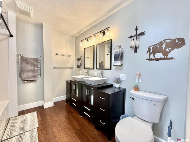 26855 SW 89th Rd, Beatrice, NE 68310 - bathroom with wood finished floors, double vanity, and a textured ceiling