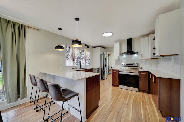 1991 Calvert St, Lincoln, NE 68502 - kitchen with wall chimney exhaust hood, appliances with stainless steel finishes, a peninsula, a kitchen breakfast bar, and light wood-type flooring
