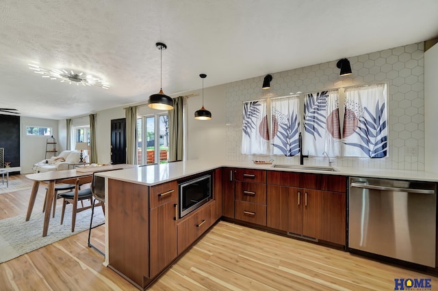 1991 Calvert St, Lincoln, NE 68502 - kitchen featuring stainless steel appliances, a peninsula, light wood-style floors, light countertops, and open floor plan
