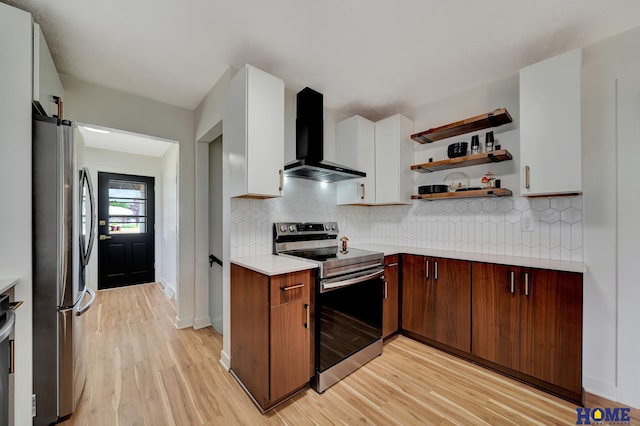 1991 Calvert St, Lincoln, NE 68502 - kitchen featuring appliances with stainless steel finishes, wall chimney range hood, light countertops, light wood-type flooring, and backsplash