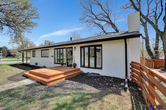 1991 Calvert St, Lincoln, NE 68502 - back of house with a wooden deck, a chimney, and a shingled roof
