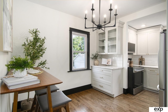 3814 Marcy St, Omaha, NE 68105 - kitchen featuring stainless steel appliances, a chandelier, backsplash, light wood-style floors, and glass insert cabinets