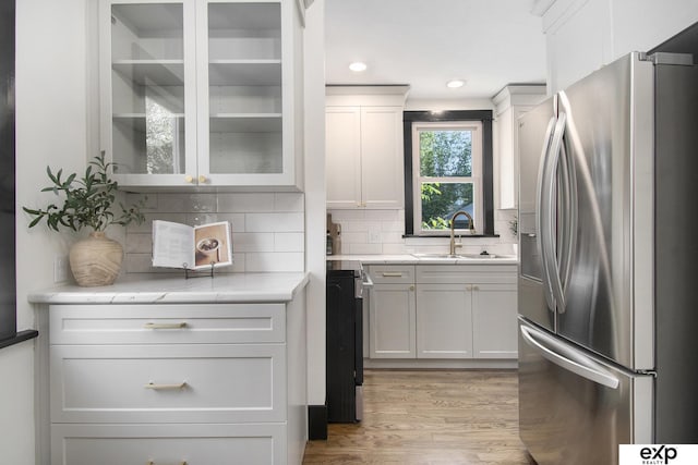 3814 Marcy St, Omaha, NE 68105 - kitchen with stainless steel fridge, decorative backsplash, light wood-type flooring, white cabinetry, and glass insert cabinets