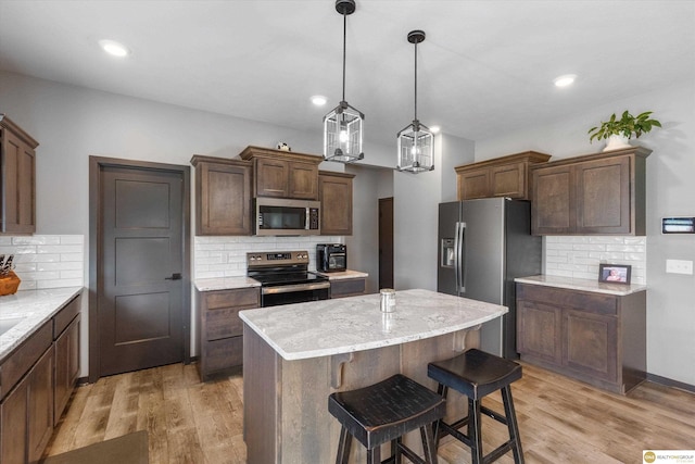 7176 N 166th St, Bennington, NE 68007 - kitchen with appliances with stainless steel finishes, backsplash, light wood-style floors, a kitchen island, and recessed lighting