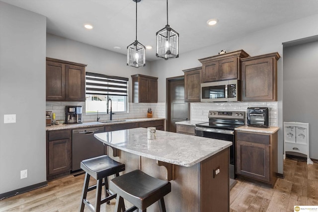 7176 N 166th St, Bennington, NE 68007 - kitchen with stainless steel appliances, a kitchen island, dark brown cabinets, tasteful backsplash, and light wood-style flooring