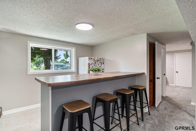 4005 N 213th Cir, Omaha, NE 68022 - kitchen featuring a textured ceiling, freestanding refrigerator, a breakfast bar area, butcher block counters, and a peninsula