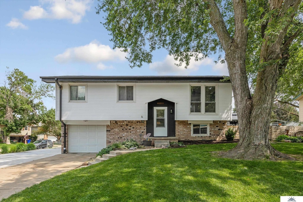 7713 Chestnut St, La Vista, NE 68128 - raised ranch featuring driveway, a garage, a front lawn, brick siding, and entry steps