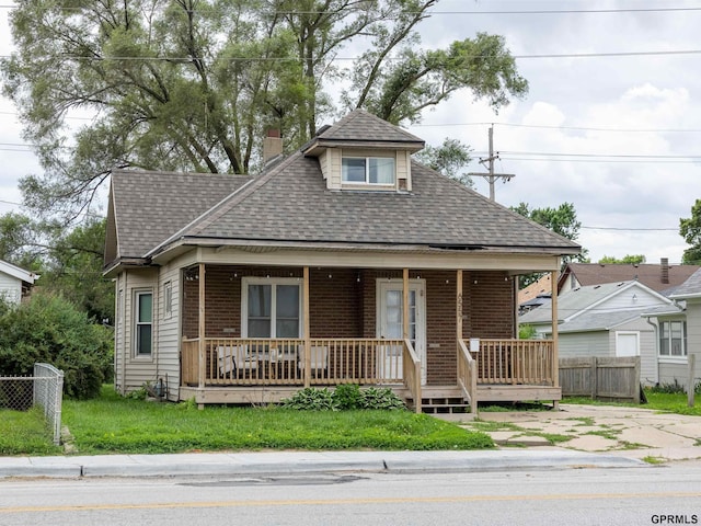 6557 Maple St, Omaha, NE 68104 - view of front facade featuring roof with shingles, covered porch, a chimney, and brick siding