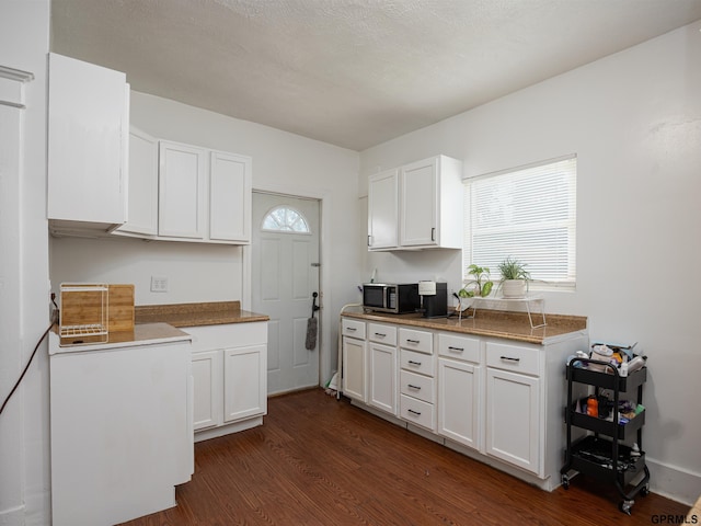 6557 Maple St, Omaha, NE 68104 - kitchen with stainless steel microwave, dark wood finished floors, white cabinets, and healthy amount of natural light