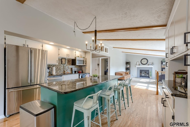 1524 Trumball Ter, Plattsmouth, NE 68048 - kitchen with appliances with stainless steel finishes, a textured ceiling, a center island, a chandelier, and a glass covered fireplace