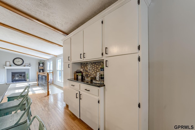 1524 Trumball Ter, Plattsmouth, NE 68048 - kitchen featuring light wood-type flooring, dark countertops, backsplash, white cabinets, and a textured ceiling