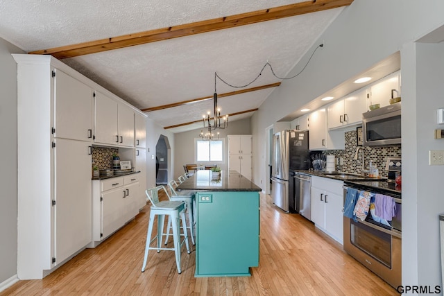 1524 Trumball Ter, Plattsmouth, NE 68048 - kitchen featuring stainless steel appliances, dark countertops, a center island, white cabinetry, and backsplash