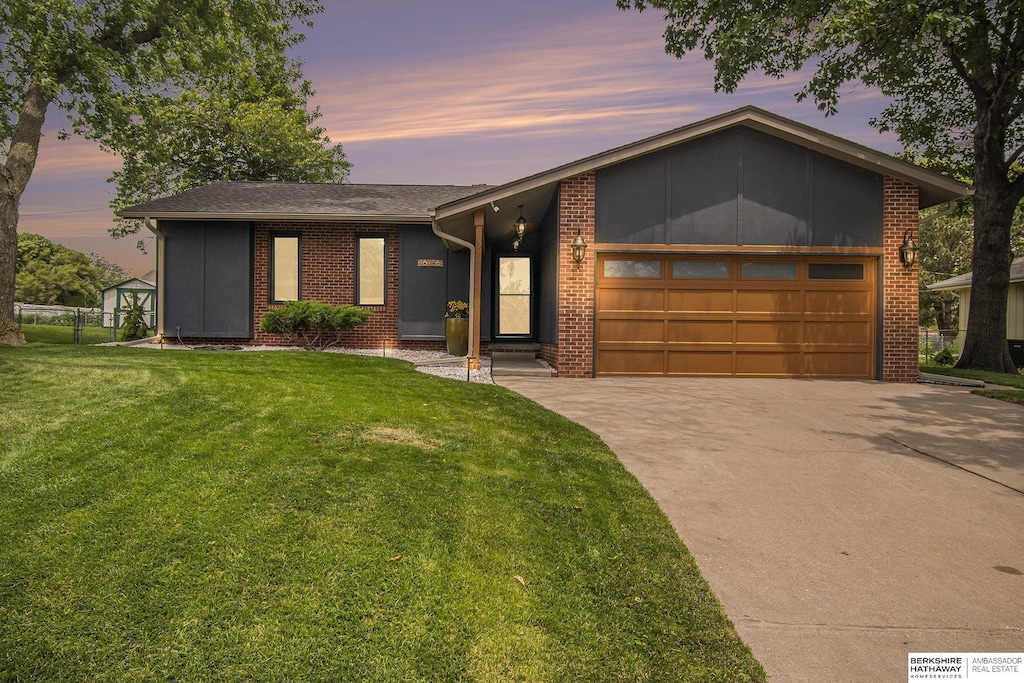 16756 William St, Omaha, NE 68130 - mid-century home with a garage, driveway, a lawn, brick siding, and a shingled roof