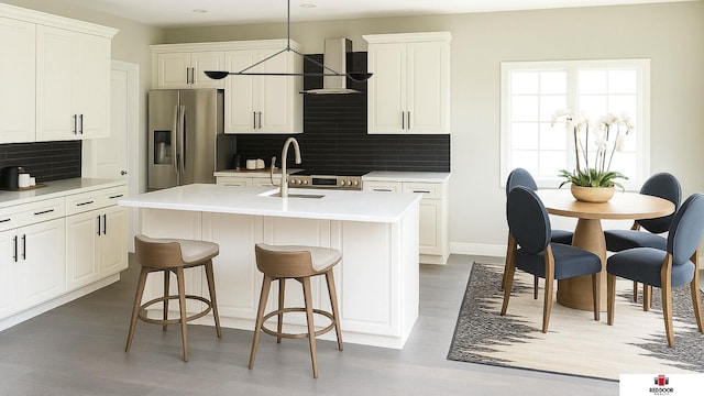 4608 S 1st St, Lincoln, NE 68512 - kitchen with stainless steel fridge, wall chimney exhaust hood, decorative backsplash, a center island with sink, and light countertops