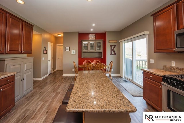 15929 Rosewater Pkwy, Bennington, NE 68007 - kitchen with stainless steel appliances, wood finished floors, light stone counters, and recessed lighting
