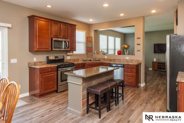 15929 Rosewater Pkwy, Bennington, NE 68007 - kitchen featuring appliances with stainless steel finishes, light wood-style flooring, a breakfast bar area, recessed lighting, and a kitchen island