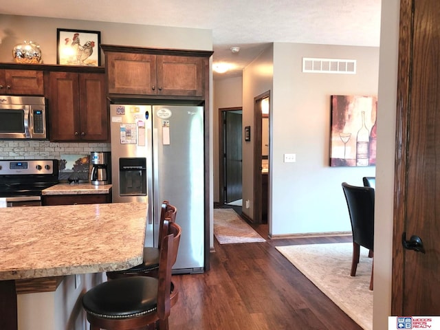 2364 N Columbia Ave, Seward, NE 68434 - kitchen with stainless steel appliances, dark wood-type flooring, decorative backsplash, light countertops, and a breakfast bar area