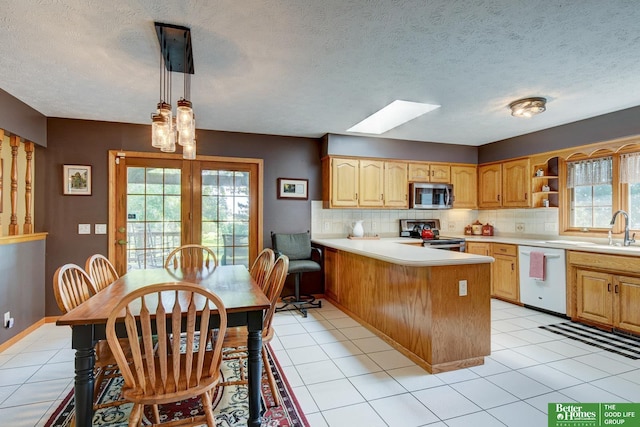 21900 Angus Rd, Gretna, NE 68028 - kitchen with appliances with stainless steel finishes, a skylight, a peninsula, light countertops, and decorative backsplash