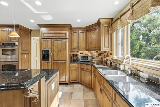 1705 N 102nd St, Omaha, NE 68114 - kitchen featuring double oven, paneled fridge, backsplash, brown cabinets, and hanging light fixtures