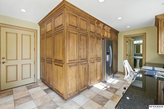 1705 N 102nd St, Omaha, NE 68114 - kitchen with stainless steel refrigerator with ice dispenser, dark stone countertops, brown cabinets, recessed lighting, and light tile patterned floors