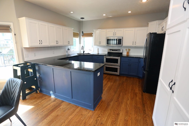 11915 S 53rd St, Papillion, NE 68133 - kitchen with appliances with stainless steel finishes, a peninsula, dark wood-type flooring, blue cabinets, and recessed lighting