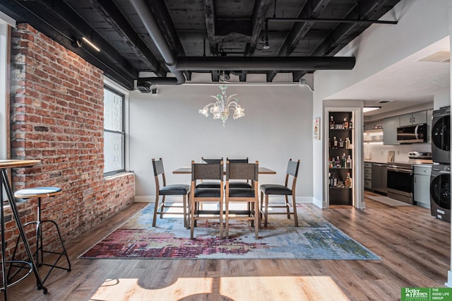 312 S 16th St Unit 904, Omaha, NE 68102 - dining room with estacked washer and dryer, brick wall, wood finished floors, and a chandelier