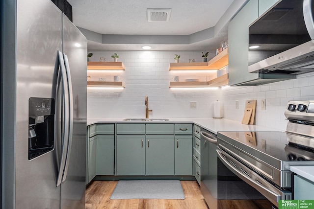 312 S 16th St Unit 904, Omaha, NE 68102 - kitchen with stainless steel appliances, open shelves, green cabinets, light wood-style flooring, and light countertops