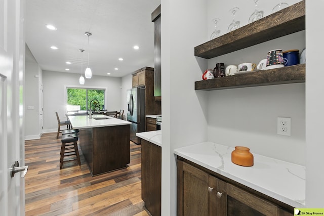 15436 Fowler Ave, Omaha, NE 68116 - kitchen with dark wood-style floors, recessed lighting, an island with sink, a kitchen bar, and decorative light fixtures