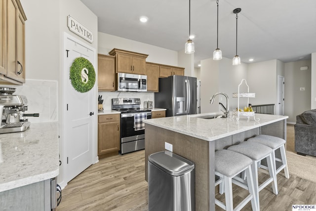 5003 N 180th Ave, Elkhorn, NE 68022 - kitchen featuring appliances with stainless steel finishes, light wood-style flooring, a breakfast bar area, brown cabinets, and open floor plan