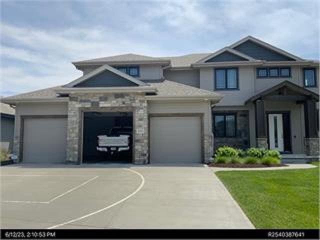 20761 Shirley St, Omaha, NE 68022 - view of front of property with a garage, concrete driveway, stone siding, and a front yard