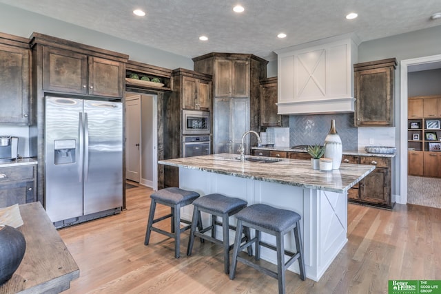 20761 Shirley St, Omaha, NE 68022 - kitchen featuring appliances with stainless steel finishes, light stone countertops, light wood-type flooring, a kitchen breakfast bar, and dark brown cabinetry