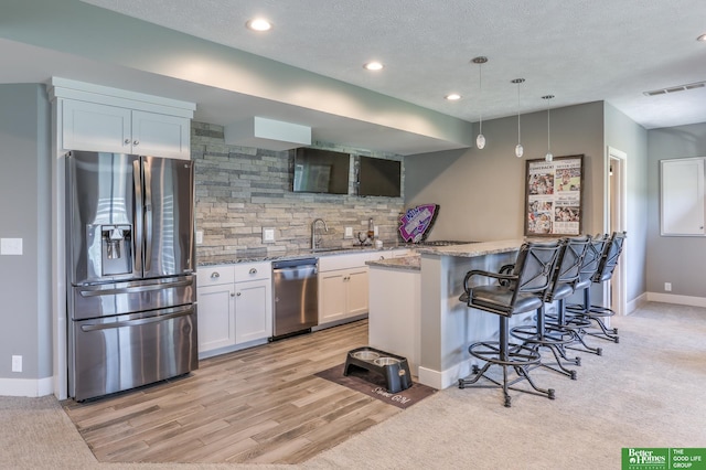 20761 Shirley St, Omaha, NE 68022 - kitchen featuring appliances with stainless steel finishes, tasteful backsplash, a kitchen breakfast bar, white cabinetry, and light stone countertops