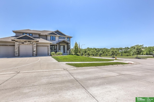 20761 Shirley St, Omaha, NE 68022 - view of front of house featuring a front yard, concrete driveway, a garage, stone siding, and roof with shingles