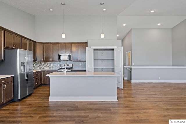 7530 Augustine Ave, Lincoln, NE 68516 - kitchen with appliances with stainless steel finishes, dark brown cabinetry, light countertops, a center island with sink, and backsplash