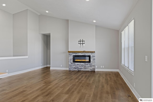 7530 Augustine Ave, Lincoln, NE 68516 - unfurnished living room featuring vaulted ceiling, a glass covered fireplace, healthy amount of natural light, wood finished floors, and recessed lighting