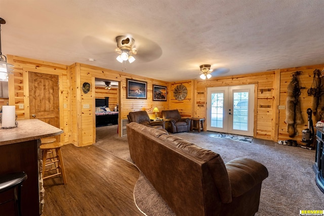 817 S 3rd St, Nebraska City, NE 68410 - living area featuring wood walls, french doors, a ceiling fan, a textured ceiling, and dark wood finished floors