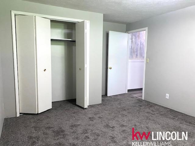 2930 Drawbridge Ct, Lincoln, NE 68516 - unfurnished bedroom with carpet flooring, a closet, and a textured ceiling