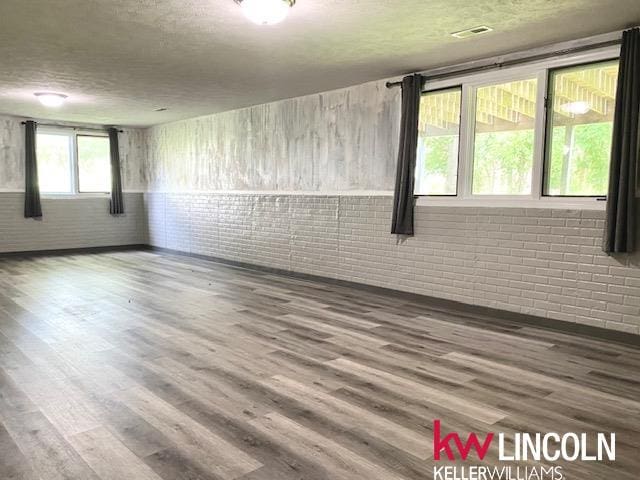 2930 Drawbridge Ct, Lincoln, NE 68516 - empty room with brick wall, wood finished floors, and a textured ceiling
